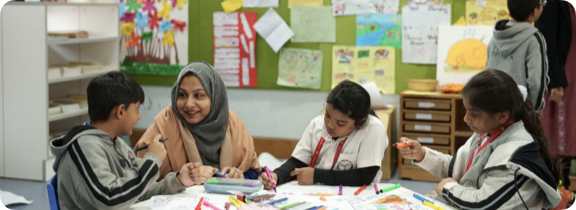 Teacher with students inside a classroom sitting at a table.